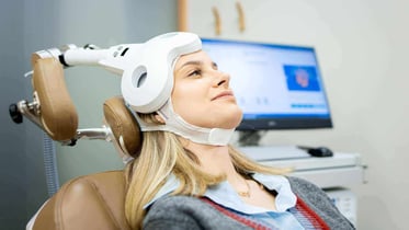 Mujer durante una sesión de estimulación cerebral no invasiva, con el cabezal apoyado sobre la cabeza