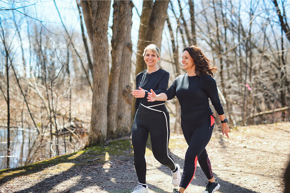 Dos mujeres de mediana edad corriendo al aire libre como hábito de actividad física para prevenir el Alzheimer