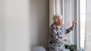 mujer mayor mirando por la ventana